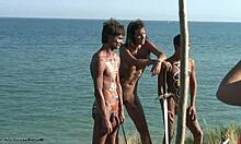 Chaudasses en body tribal posant avec des épées et de la merde sur une plage